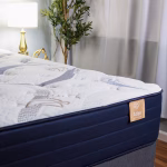 Corner shot of Atlas mattress, showing its detailed, textured quilt, and silk flag with logo